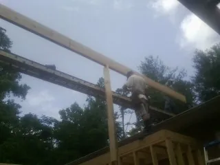 Carpenter setting a ridge beam over a new addition frame — Ice Dam Removal by Roofing Brothers in Flint Hill