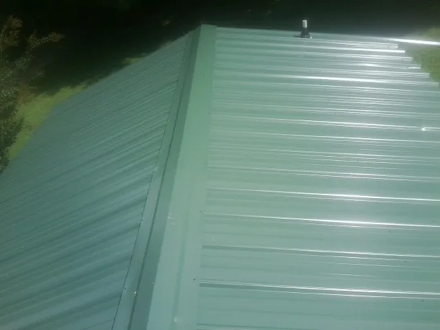 New green metal panels meeting at the ridge of a roof — Flat Roof Repair work by our crew in Flint Hill