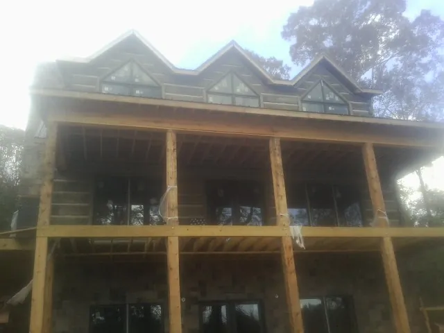Dormers and porch framing on a large log home under construction — Roof Coating work by our crew in Flint Hill