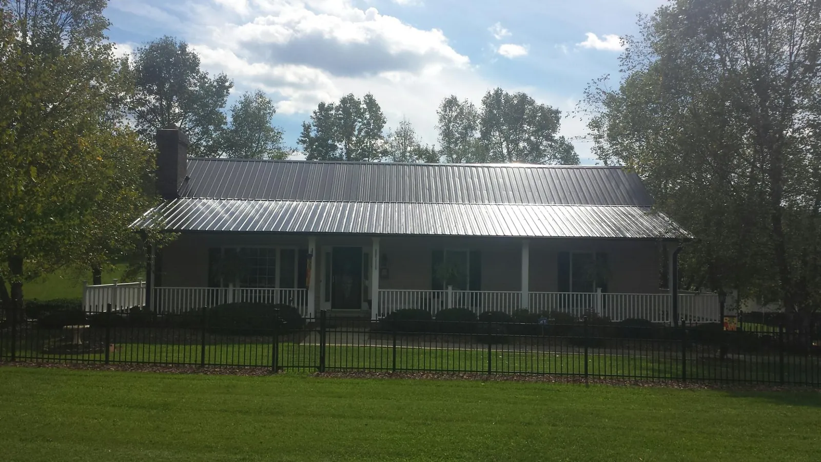 Gray metal roof on a brick ranch with a full width front porch — Gutter Guard Installation work by our crew in Flint Hill