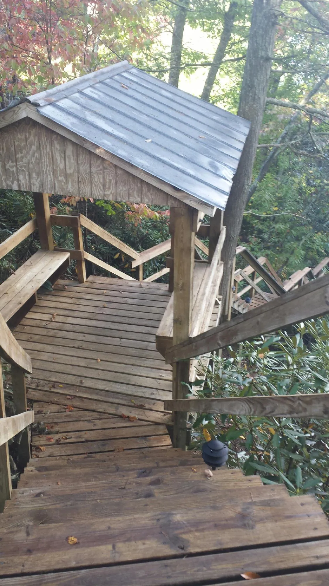 Metal roofed shelter over wooden steps on a wooded walkway — Skylight Repair & Installation work by our crew in Flint Hill