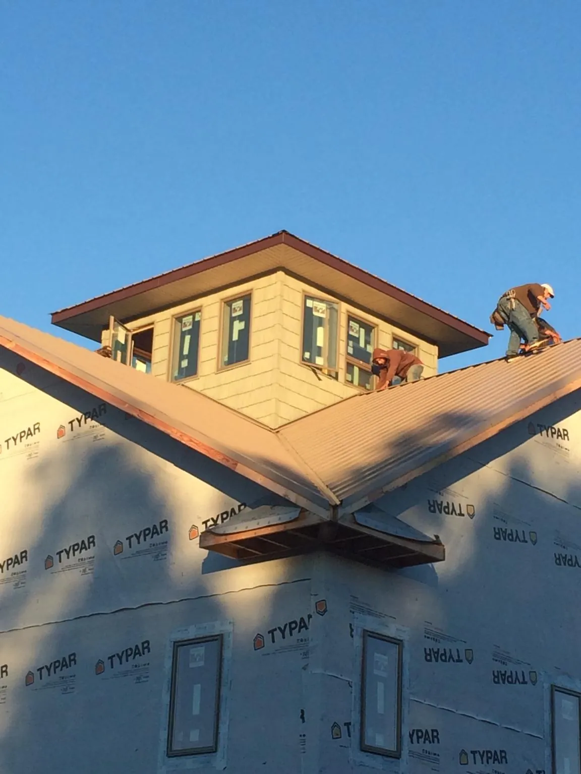 Roofers working around a rooftop cupola on a new metal roof at sunset — Roof Waterproofing in Flint Hill by Roofing Brothers
